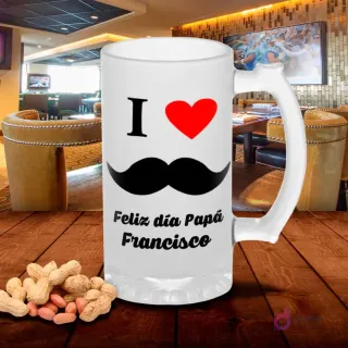 Jarra de cerveza esmerilada con diseño 'I ❤️ Papá Feliz día Papá Francisco' con corazón rojo y bigote negro, sobre mesa de madera con cacahuetes, fondo de bar. Plantilla Día del Padre con nombre.