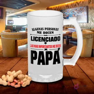 Chopp de vidrio esmerilado con diseño 'Algunas personas me dicen LICENCIADO Las más importantes me dicen PAPÁ' y estrella, sobre mesa de madera con cacahuetes, fondo de bar. Plantilla sublimación Licenciado Papá.