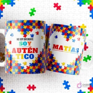 Dos tazas blancas con diseños de autismo sobre un fondo de piezas de puzzle. Una dice 'NO SOY DIFERENTE SOY AUTÉNTICO' y la otra lleva el nombre 'MATÍAS'.
