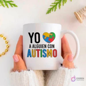 Manos sujetando una taza blanca con la frase 'YO ❤️ A ALGUIEN CON AUTISMO' donde el corazón es un puzzle de colores.