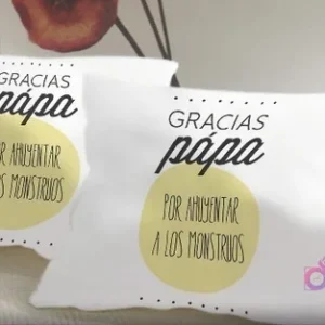 Pareja de cojines blancos sublimados con el mensaje humorístico 'Gracias papá por alimentar a los monstruos' en un círculo amarillo y letras negras, divertido regalo para padres.