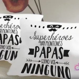 Cojines blancos sublimados con la frase 'Superhéroes hay montones Papas como vos NINGUNO' en negro, con un icono de bigote y máscara, un mensaje único y emotivo.