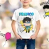 Niño sonriendo con camiseta blanca personalizada con el nombre 'FRANCO' y un superhéroe infantil de traje azul y amarillo