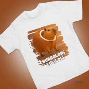 Polera blanca con diseño animado de capibara adorable dentro de un coco, con fondo marrón.