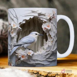 Taza sublimada con ave azul claro 3D en un nido rocoso con relieve, rodeada de flores blancas y rosadas.
