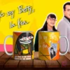 Dos tazas de sublimación con diseños de Flork Betty la Fea, una con la frase 'LA VIDA SE ME ESTÁ YENDO DE LAS MANOS' y otra con Betty Pinzón original, sobre mesa de madera con fondo amarillo y personajes de la telenovela.