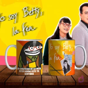 Dos tazas de sublimación con diseños de Flork Betty la Fea, una con la frase 'LA CABECERA DE LA MESA ESTÁ DONDE ESTÉ SENTADA' y otra con Betty Pinzón original, sobre mesa de madera con fondo amarillo y personajes de la telenovela.
