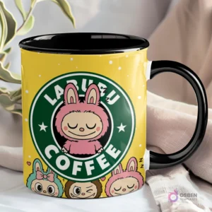 Taza amarilla con interior y asa negros, presentando el logo 'LABUBU COFFEE' con un Labubu rosa de ojos cerrados y otros Labubu en la base.