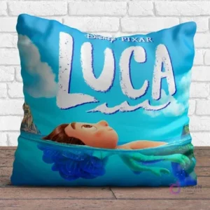 Cojín cuadrado sublimado con el personaje Luca de Disney Pixar en forma humana emergiendo del agua, con el logo, sobre un fondo azul claro.