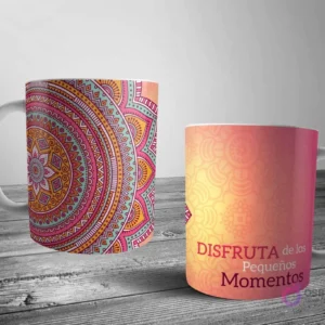 Dos tazas blancas con un diseño de mandala detallado. Una con un gran mandala rosa-teal-naranja y la otra con un patrón más sutil y la frase 'DISFRUTA de los Pequeños Momentos' en tonos cálidos.