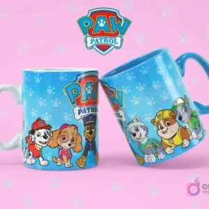 Taza de sublimación blanca con Marshall, Skye y Chase, junto a una taza azul con el logo de Paw Patrol, sobre fondo rosa con huellas.