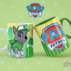 Taza de sublimación blanca con Rocky de Paw Patrol, junto a una taza verde con el logo de Paw Patrol, sobre fondo verde claro con huellas.