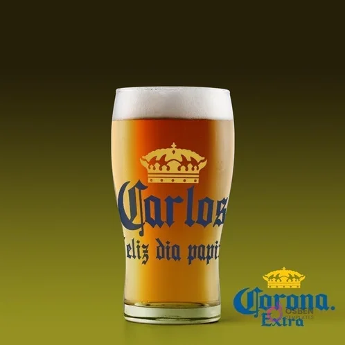 Vaso de cerveza con etiqueta personalizada 'Carlos Feliz día papito' inspirada en Cerveza Corona, fondo verde oscuro. Vaso de cerveza con etiqueta personalizada 'Carlos Feliz día papito' inspirada en Cerveza Corona, fondo verde oscuro.