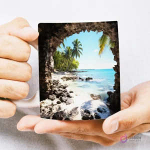 Mug con diseño 3D de una playa tropical paradisíaca con palmeras y mar turquesa, visto desde el interior de una cueva rocosa, sostenido por manos.