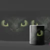 Primer plano de los ojos verdes brillantes y la piel escamosa oscura de Chimuelo de Cómo Entrenar a tu Dragón en un mockup de taza negra.