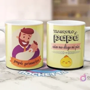 Dos tazas blancas de sublimación con fondo amarillo. Una con caricatura de padre barbudo cargando un bebé y 'papá primerizo'. Otra con frase 'TRANQUILO papá aún no digo ni pío' y un pollito.