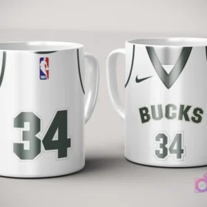 Par de tazas de sublimación con diseño de jersey blanco y verde de Milwaukee Bucks, número 34, con logo Nike y logotipo NBA, sobre fondo gris claro.
