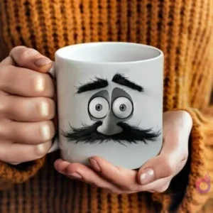 Manos sosteniendo una taza blanca con un diseño 3D de ojos y un gran bigote negro de un padre barbudo, estilo caricatura, sobre un fondo de suéter de lana marrón.