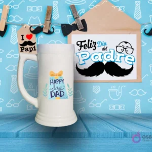 Shoperos blanco con diseño de sublimación 'HAPPY DAY DAD' en tonos verdes y azules con un dibujo de caja de regalo, sobre fondo azul decorativo.