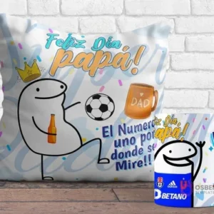 Cojín y taza sublimados con diseños Flork del Día del Padre. El cojín muestra un Flork jugando fútbol con una cerveza y el mensaje 'Feliz Día Papá! El Número uno por donde se Mire!!', y la taza tiene un Flork saludando con el logo de Universidad de Chile.