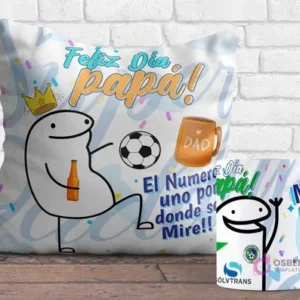 Cojín y taza sublimados con diseños Flork del Día del Padre. El cojín muestra un Flork jugando fútbol con una cerveza y el mensaje 'Feliz Día Papá! El Número uno por donde se Mire!!', y la taza tiene un Flork saludando con el logo de Cobreloa.