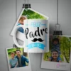 Taza blanca de sublimación con diseño 'Feliz Padre Día Del' y un bigote, rodeada de fotografías de padres con sus hijos colgando de clips en un fondo gris.