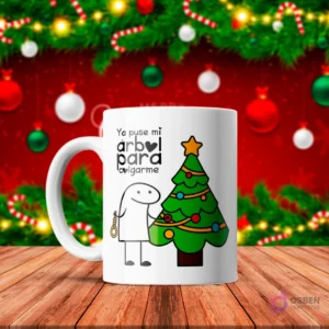 Taza de sublimación blanca con Flork junto a un árbol de Navidad decorado, sosteniendo una soga, texto 'Ya puse mi árbol para colgarme' con fondo rojo festivo.
