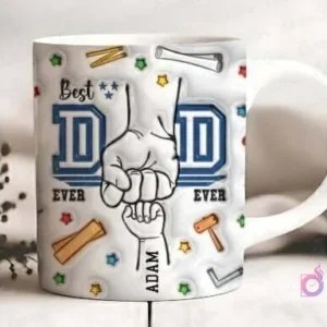 Vista frontal de una taza blanca sublimada con el diseño 'Best DAD EVER', mostrando el puño de un padre y una mano de niño con el nombre 'ADAM', rodeado de pequeñas herramientas de bricolaje sobre un fondo difuminado.