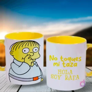 Par de tazas con tema de Los Simpsons, una con Ralph Wiggum chupándose el dedo y la otra con el texto 'No toques mi taza HOLA SOY RAFA', ambas con el interior amarillo, en un entorno exterior al atardecer.