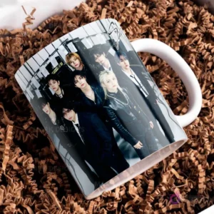 Taza blanca con el logo de Stray Kids y otra foto grupal, los miembros con atuendos oscuros de cuero, posando con estilo y seriedad.