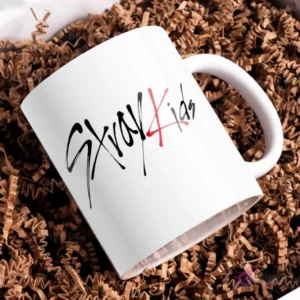 Taza blanca sencilla con el logo distintivo de Stray Kids en letras negras y rojas, fondo liso.