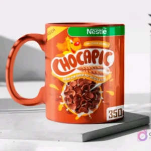 Taza de cerámica color cobre brillante sublimada con el diseño del cereal Chocapic de Nestlé, mostrada en un mockup sobre una base gris clara.