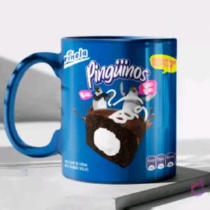 Taza de cerámica color azul brillante sublimada con el diseño de los pastelitos Pingüinos de Marinela y sus etiquetas de advertencia, en un mockup.
