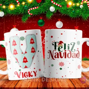 Taza sublimada con la letra V mayúscula en turquesa adornada con campanas, junto al nombre 'VICKY' y al reverso 'Feliz Navidad' con estrellas y copos de nieve.